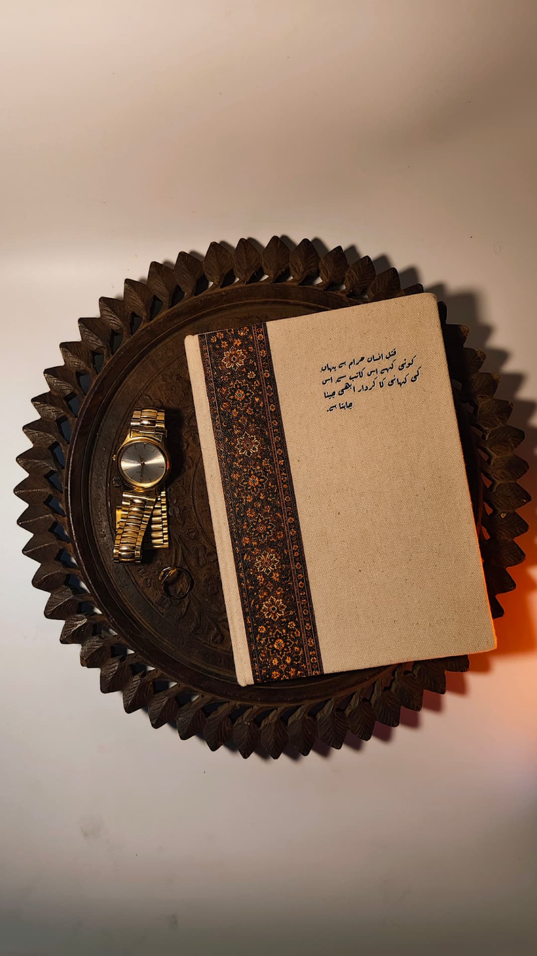 Kaatib diary in Urdu typography resting on a carved wooden tray