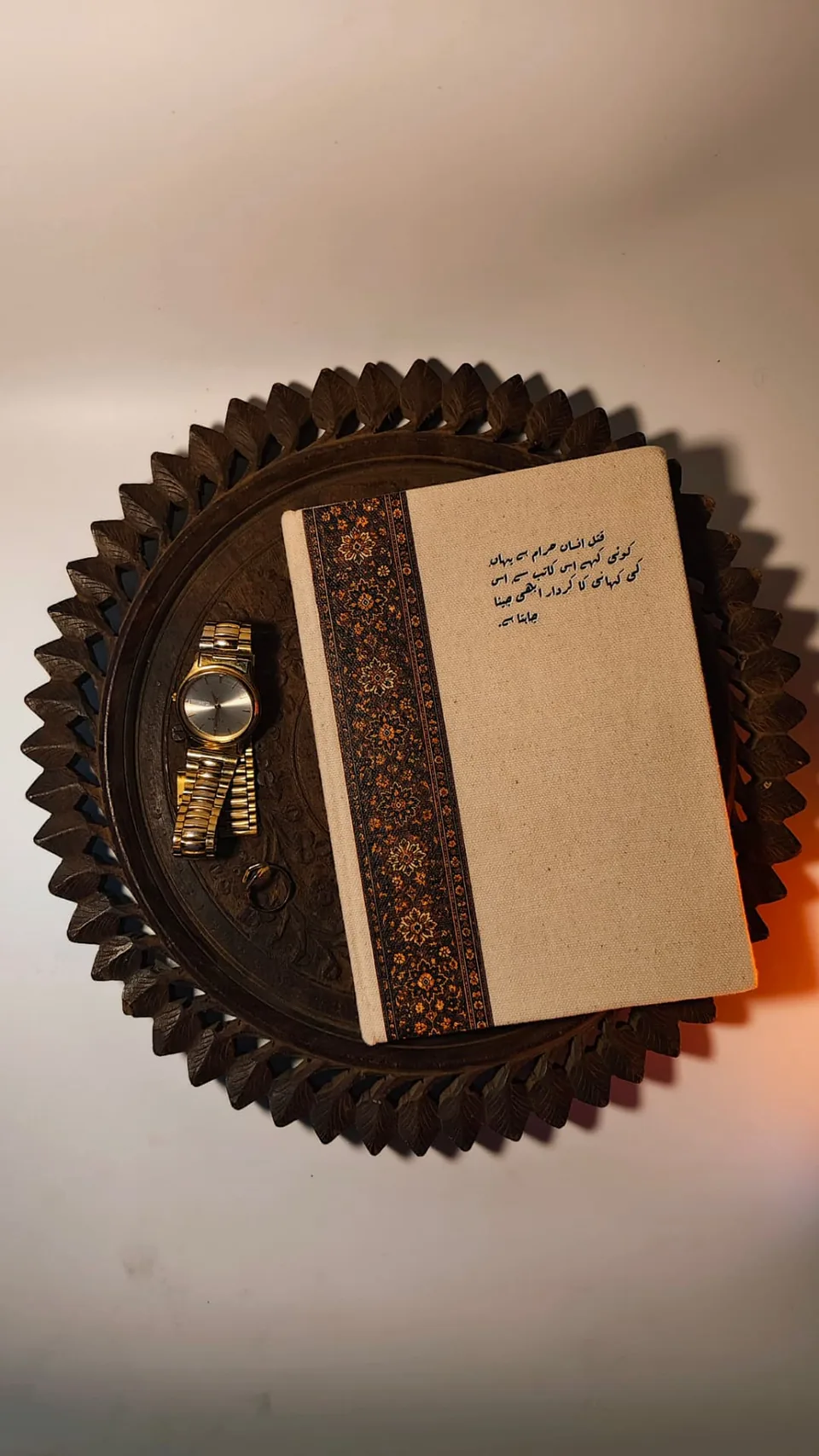 Kaatib diary in Urdu typography resting on a carved wooden tray