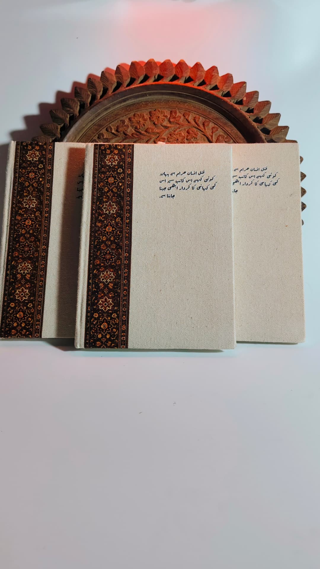 Three Kaatib diaries fanned out beside a carved wooden tray